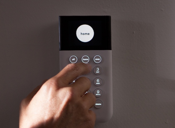 Hand about to press button on keypad displaying the word 'home' in a white circle